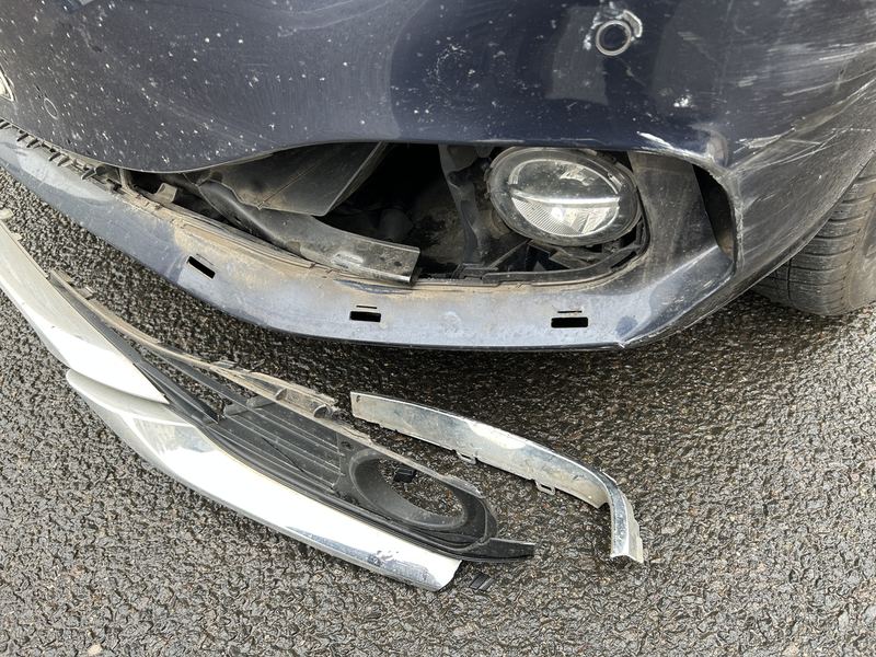 Abgerissener vorderer Stoßfänger eines dunkelblauen BMW 4er Gran Coupé mit freiliegendem Nebelscheinwerfer, Reparaturkosten laut Gutachten 6.899 Euro brutto