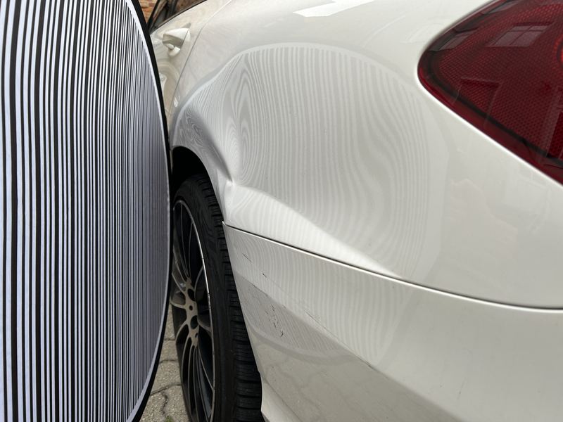 Hintere linke Seitenwand eines weißen Mercedes C-Klasse T-Modell am Rücklicht unter der Dellenleuchte, die Streifen zeigen die eingedrückte Fläche, Reparaturkosten laut Gutachten 15.852 Euro brutto