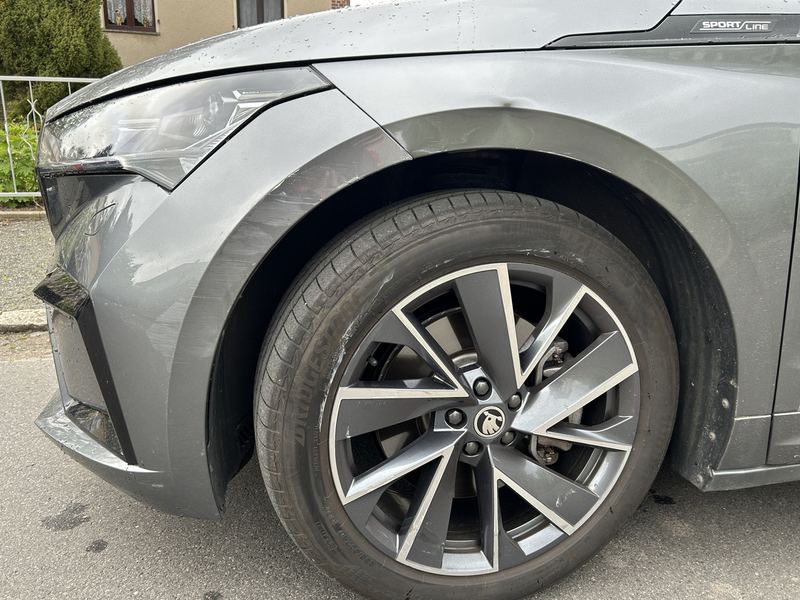 Vorderer linker Kotflügel eines grauen Škoda Enyaq mit Delle und Kratzern über dem Radlauf, Reparaturkosten laut Gutachten 9.520 Euro brutto