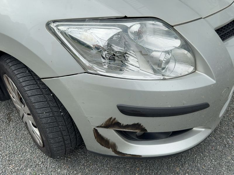 Vordere linke Ecke eines silbernen Toyota Auris mit Schrammen am Stoßfänger und Kotflügel, Reparaturkosten laut Gutachten 4.219 Euro brutto